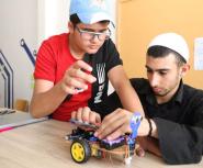 Two teenage boys in hats build a robot vehicle