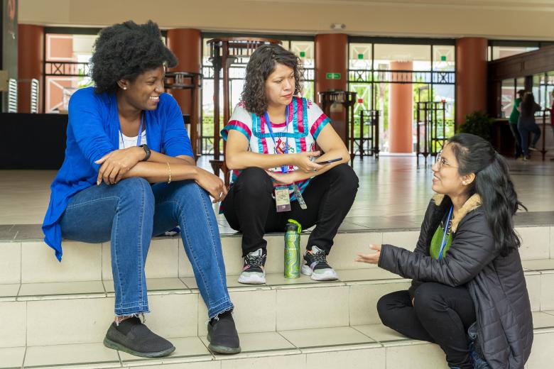 Three diverse women sit conversing on steps