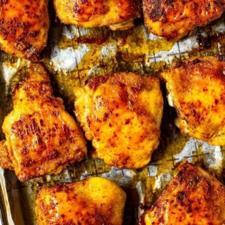 Baked chicken thighs on a wire rack on a sheet pan