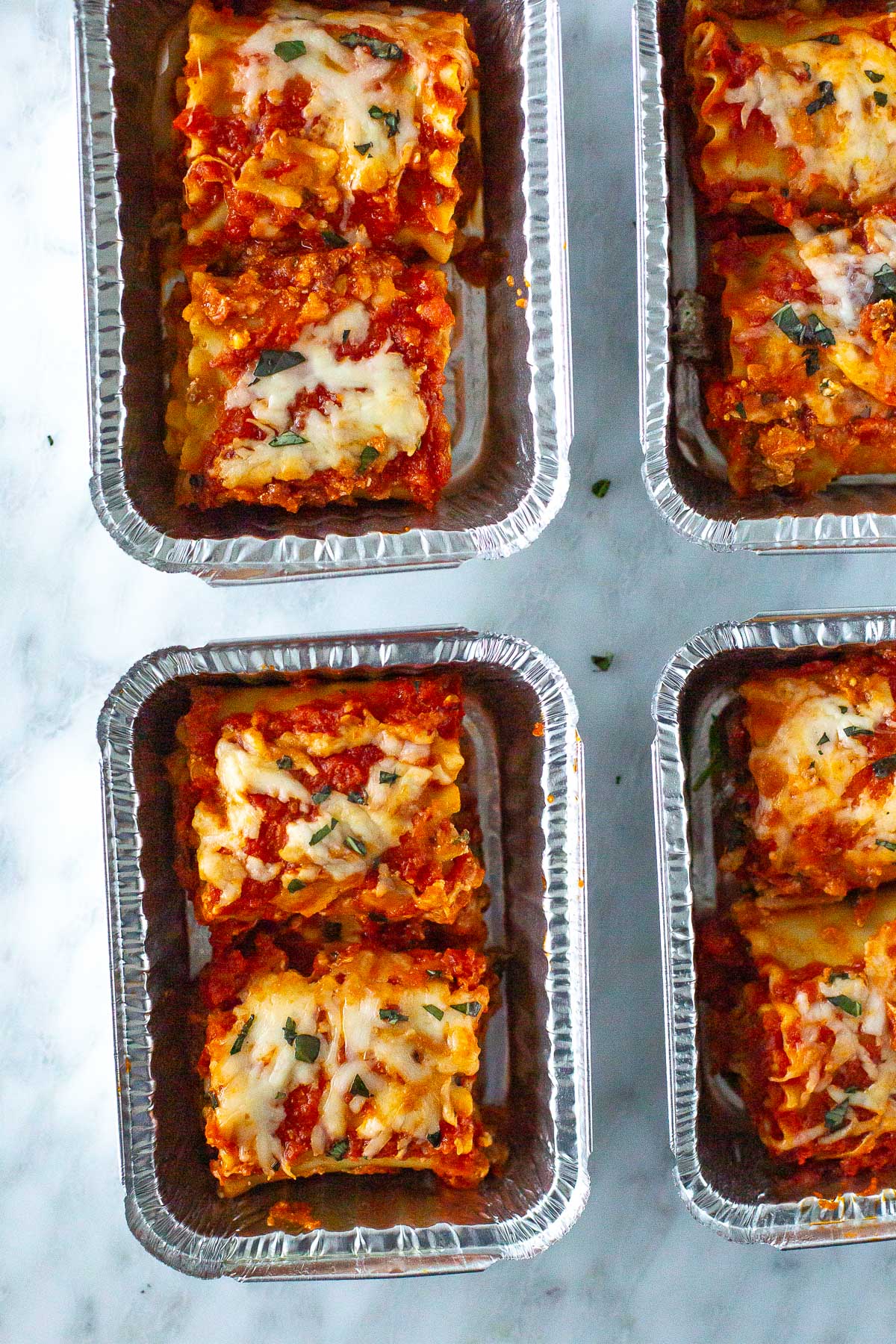Lasagna roll-ups packed into meal prep containers, ready for storage or freezing.