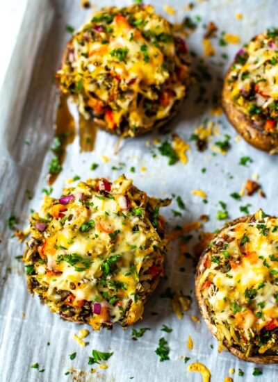 Stuffed portobello mushrooms on a sheet pan lined with parchment paper.