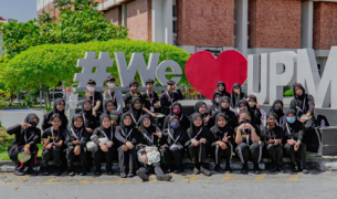 A large group of Asian teenagers, all wearing black, pose in front of a sign that says #We(heart)UPM